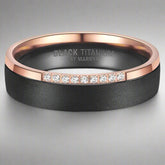 Black titanium ring with rose gold band and diamond accents on a white background